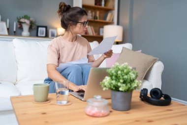 Genç kadın serbest çalışan küçük bir şirket sahibi dizüstü bilgisayarında verilerle vergi iadesi hesaplıyor. İç işlerinde çalışmak, profesyonel meslekte kadın modern teknoloji kullanıcısı..