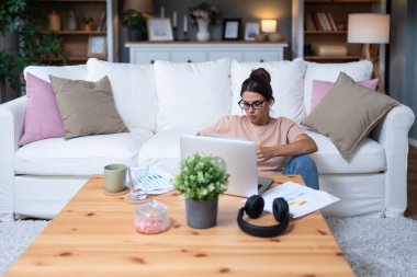 Genç kadın serbest çalışan küçük bir şirket sahibi dizüstü bilgisayarında verilerle vergi iadesi hesaplıyor. İç işlerinde çalışmak, profesyonel meslekte kadın modern teknoloji kullanıcısı..