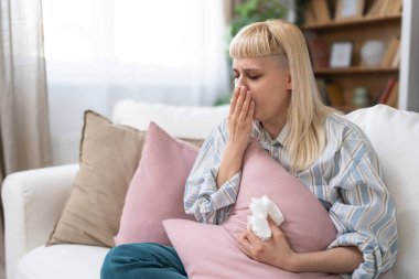 Kanepede oturan genç bir kadını üzeceğim. Burnu donan bir battaniyeyle kaplanmış. Ateşi var, mendile hapşırıyor.