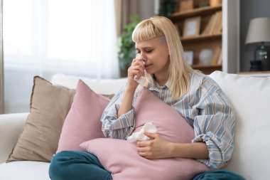 Kanepede oturan genç bir kadını üzeceğim. Burnu donan bir battaniyeyle kaplanmış. Ateşi var, mendile hapşırıyor.