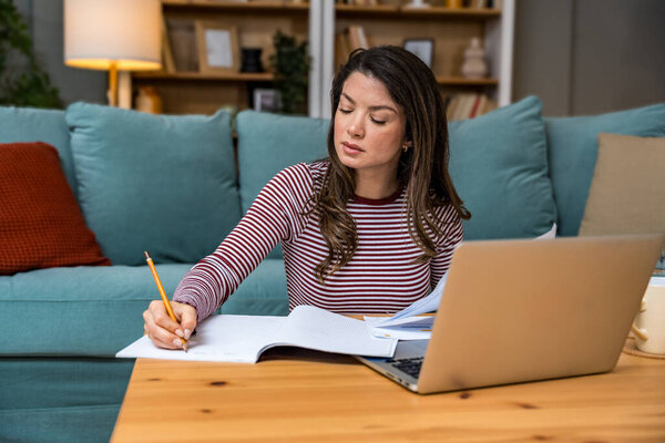 Young woman freelance worker small startup company business owner calculating tax return with data on laptop computer. Working at home office, professional occupation female modern technology user.