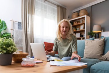 Genç kadın serbest çalışan küçük bir şirket sahibi dizüstü bilgisayarında verilerle vergi iadesi hesaplıyor. İç işlerinde çalışmak, profesyonel meslekte kadın modern teknoloji kullanıcısı..