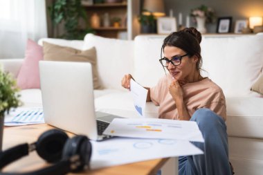 Genç kadın serbest çalışan küçük bir şirket sahibi dizüstü bilgisayarında verilerle vergi iadesi hesaplıyor. İç işlerinde çalışmak, profesyonel meslekte kadın modern teknoloji kullanıcısı..