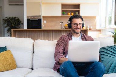 Genç iş adamı küçük bir şirket sahibi, evde çalışıyor, grafikleri ve dizüstü bilgisayarları kontrol ediyor. Yeni ürün stratejisinin maliyetlerini ve giderlerini hesaplayan yenilikçi genç serbest erkek.