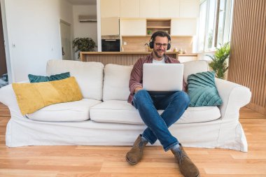 Genç iş adamı küçük bir şirket sahibi, evde çalışıyor, grafikleri ve dizüstü bilgisayarları kontrol ediyor. Yeni ürün stratejisinin maliyetlerini ve giderlerini hesaplayan yenilikçi genç serbest erkek.