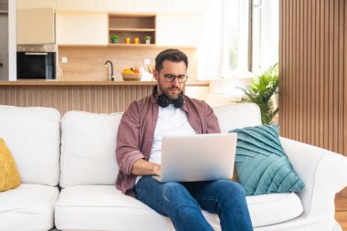 Genç iş adamı küçük bir şirket sahibi, evde çalışıyor, grafikleri ve dizüstü bilgisayarları kontrol ediyor. Yeni ürün stratejisinin maliyetlerini ve giderlerini hesaplayan yenilikçi genç serbest erkek.