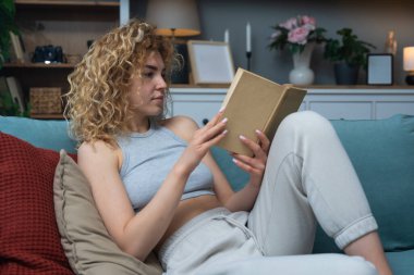 Evdeki rahat koltukta kitap okurken huzurlu yalnızlığın tadını çıkaran genç bir kadın. Günlük kıyafetlerle rahatlıyor, gerçeklerden kaçıyor, öğreniyor, hayal kuruyor ve sessiz anlarda huzur buluyor.