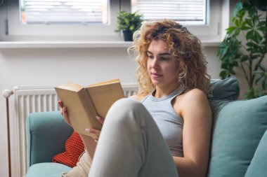 Evdeki rahat koltukta kitap okurken huzurlu yalnızlığın tadını çıkaran genç bir kadın. Günlük kıyafetlerle rahatlıyor, gerçeklerden kaçıyor, öğreniyor, hayal kuruyor ve sessiz anlarda huzur buluyor.