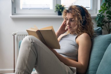 Evdeki rahat koltukta kitap okurken huzurlu yalnızlığın tadını çıkaran genç bir kadın. Günlük kıyafetlerle rahatlıyor, gerçeklerden kaçıyor, öğreniyor, hayal kuruyor ve sessiz anlarda huzur buluyor.