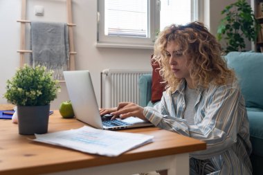 Yerde dizüstü bilgisayar üzerinde çalışırken odaklanma sorunu yaşayan genç bir kadın, basılı analitik, hiperaktivite bozukluğu, zihinsel yorgunluk, tükenmişlik ve modern çoklu görev beklentilerinin baskısı ile mücadele ediyor.