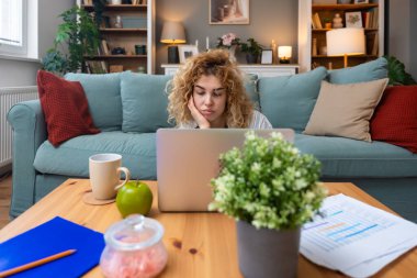 Yerde dizüstü bilgisayar üzerinde çalışırken odaklanma sorunu yaşayan genç bir kadın, basılı analitik, hiperaktivite bozukluğu, zihinsel yorgunluk, tükenmişlik ve modern çoklu görev beklentilerinin baskısı ile mücadele ediyor.