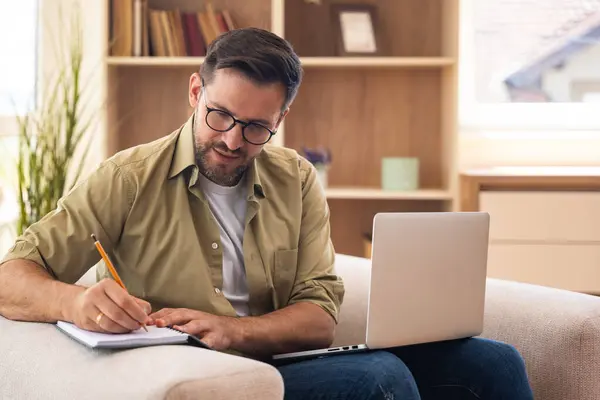 Sanal danışmanlık oturumunda evde yaşayan genç bir terapist, videodaki müşteriyi dinleyen zihinsel sağlık uzmanı sakin iç ortamlarda destek ve empati sunan notlar alıyor.
