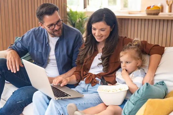 Mutlu, genç bir aile evlerinde kanepede oturup dizüstü bilgisayarda internet üzerinden internet üzerinden tatil beldesi arıyor ve küçük çocuklarıyla seyahat ediyorlar. Eğlence arayan çocuk ebeveynler.