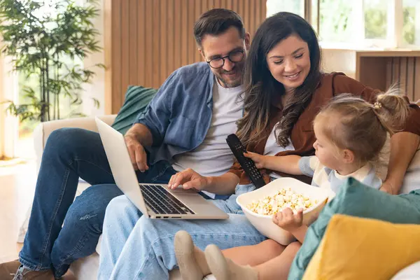 Mutlu, genç bir aile evlerinde kanepede oturup dizüstü bilgisayarda internet üzerinden internet üzerinden tatil beldesi arıyor ve küçük çocuklarıyla seyahat ediyorlar. Eğlence arayan çocuk ebeveynler.