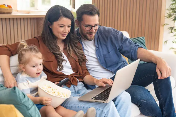 Mutlu, genç bir aile evlerinde kanepede oturup dizüstü bilgisayarda internet üzerinden internet üzerinden tatil beldesi arıyor ve küçük çocuklarıyla seyahat ediyorlar. Eğlence arayan çocuk ebeveynler.