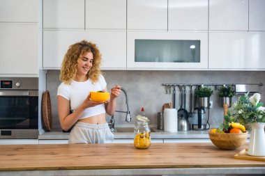 Mutfakta kahvaltı yapan güzel bir genç kadının portresi. Sağlıklı bir vücut ve sağlık için sabah yulaf ezmesi yiyen bir kız için sağlıklı bir diyet. Olumlu düşün, iyi beslen ve akıllı ol..