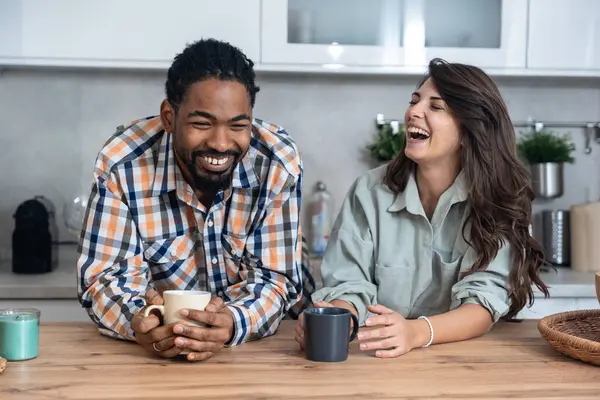Mutlu çift yeni evlerinin mutfağında kahvenin tadını çıkarıyorlar. Birlikte rahat bir sabah geçiriyorlar. Rahatlamış ve gülümsüyorlar.