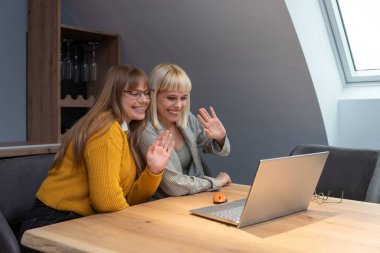 Şarap imalathanesinde pazarlama stratejisi üzerinde çalışan iki profesyonel iş kadını, laptopa odaklanmış, pozitif enerji, markalaşma fikirleri ve üzüm bağı görselleri ile çevrili..