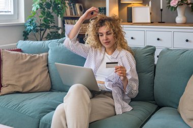 Evde elinde kredi kartı olan ve bilgisayarını online alışveriş, finansal planlama, seyahat rezervasyonu veya banka hesabı, rahat dijital yaşam tarzı ve e-ticaret konsepti için kullanan genç bir kadın.