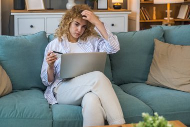 Evde elinde kredi kartı olan ve bilgisayarını online alışveriş, finansal planlama, seyahat rezervasyonu veya banka hesabı, rahat dijital yaşam tarzı ve e-ticaret konsepti için kullanan genç bir kadın.