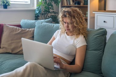 Evde çalışan ve internet bağlantısı kopukluğu, bilgisayar arızası veya sistem hatası gibi teknik sorunlar yaşayan genç bir kadın, evde otururken hayal kırıklığına uğramış ve endişeli