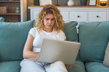 Evde çalışan ve internet bağlantısı kopukluğu, bilgisayar arızası veya sistem hatası gibi teknik sorunlar yaşayan genç bir kadın, evde otururken hayal kırıklığına uğramış ve endişeli