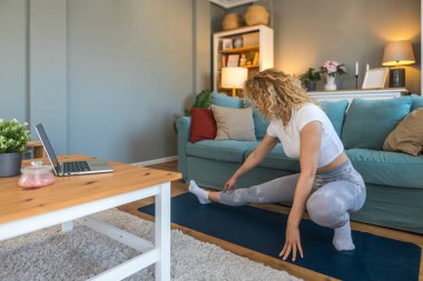 Ciddi bir araba kazasından sonra iyileşen genç bir kadın, kaslarını esneten, yoga minderi üzerinde rehabilitasyon egzersizleri yapan, bina dayanıklılığı, esneklik ve kapalı alanda esneklik sağlayan bir kadın.