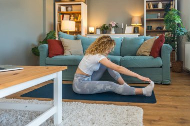 Ciddi bir araba kazasından sonra iyileşen genç bir kadın, kaslarını esneten, yoga minderi üzerinde rehabilitasyon egzersizleri yapan, bina dayanıklılığı, esneklik ve kapalı alanda esneklik sağlayan bir kadın.