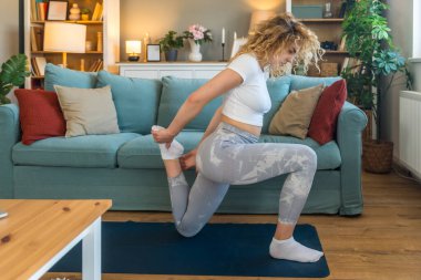 Ciddi bir araba kazasından sonra iyileşen genç bir kadın, kaslarını esneten, yoga minderi üzerinde rehabilitasyon egzersizleri yapan, bina dayanıklılığı, esneklik ve kapalı alanda esneklik sağlayan bir kadın.