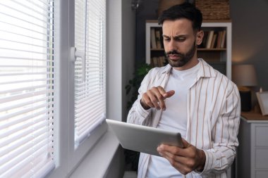 Ofiste dijital tablet üzerinde çalışan çekici bir adam. İşadamı küçük bir şirket sahibi dairesinden online olarak çalışıyor. Bağımsız serbest grafik tasarımcı erkek özgürlük ve işin tadını çıkarıyor.