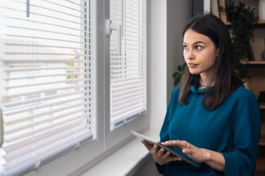 Ev ofisinde dijital tablet üzerinde çalışan çekici bir kadın. İş kadını küçük bir şirket sahibi dairesinden internet üzerinden çalışıyor. Bağımsız serbest grafik tasarımcı kadın özgürlük ve işin tadını çıkarıyor.
