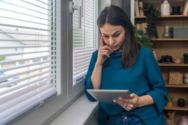 Ev ofisinde dijital tablet üzerinde çalışan çekici bir kadın. İş kadını küçük bir şirket sahibi dairesinden internet üzerinden çalışıyor. Bağımsız serbest grafik tasarımcı kadın özgürlük ve işin tadını çıkarıyor.