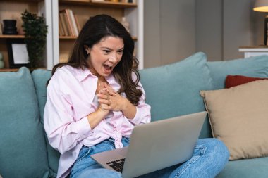 Evdeki mutlu kadın internetten randevulaşma videosu için laptop kullanıyor. Heyecanlı genç bayan, web kamerası sohbeti, sanal romantik bağlantı ve dijital ilişki deneyimi yoluyla aşk ile tanışır..