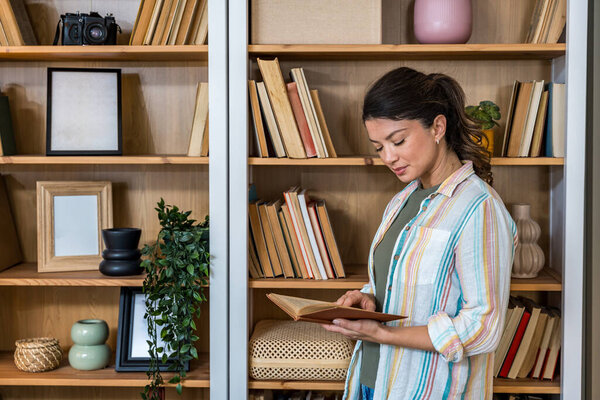 Calm woman reading a book at home, enjoying peaceful moment and personal time. Engaged in literature and relaxation, embraces quiet indoor activity for mental clarity and emotional well-being.