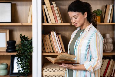 Evde kitap okuyan sakin bir kadın. Huzurlu anların ve boş zamanların tadını çıkarıyor. Edebiyat ve rahatlama ile meşgul, zihinsel berraklık ve duygusal refah için sessiz kapalı aktivite kucaklıyor.