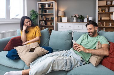 Evde akıllı telefon kullanan kıskanç bir kadınla partneri arasındaki ilişki anlaşmazlığı, iletişim sorunlarını, güven sorunlarını, duygusal gerilimi ve çiftlerde dijital dikkat dağınıklığını gösteriyor