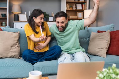 Sürpriz mutlu çift bir video görüşmesi sırasında ailelerine ve arkadaşlarına hamileliklerini duyuruyor. Gelecekteki genç ebeveynler iyi haberleri ve mutluluklarını paylaşmak için dizüstü bilgisayar kullanıyorlar..