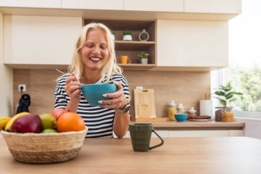 Sabah rutini, basit yaşam. Genç bir kadın mutfakta duruyor, kahve içiyor, sağlıklı kahvaltı yapıyor. Kadın girişimci evde, güne rahat ve rahat başlıyor..