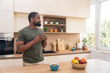 Sabah rutini, basit yaşam. Bir adam mutfakta duruyor, kahve içiyor, sağlıklı kahvaltı yapıyor. Erkek girişimci evde, güne rahat ve rahat başlıyor..