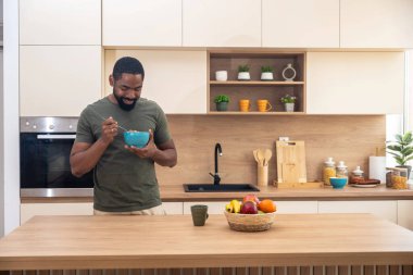 Sabah rutini, basit yaşam. Bir adam mutfakta duruyor, kahve içiyor, sağlıklı kahvaltı yapıyor. Erkek girişimci evde, güne rahat ve rahat başlıyor..