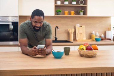 Sabah rutini, basit yaşam. Bir adam mutfakta duruyor, kahve içiyor, sağlıklı kahvaltı yapıyor. Erkek girişimci evde, güne rahat ve rahat başlıyor..