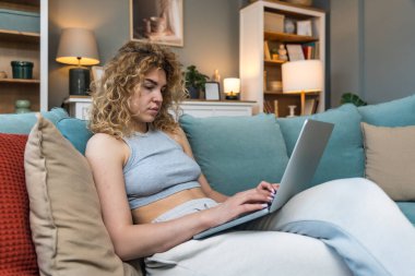 Konsantre olmuş milenyum kızı, evinde dizüstü bilgisayarla internette gezinirken tembelce hafta sonu boyunca bilgisayar sörfü yaparak internetten internet alışverişi yapmakla meşgul.