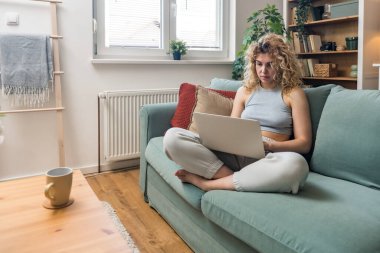 Konsantre olmuş milenyum kızı, evinde dizüstü bilgisayarla internette gezinirken tembelce hafta sonu boyunca bilgisayar sörfü yaparak internetten internet alışverişi yapmakla meşgul.