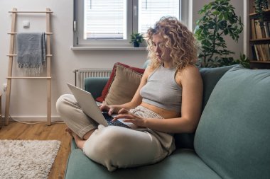 Konsantre olmuş milenyum kızı, evinde dizüstü bilgisayarla internette gezinirken tembelce hafta sonu boyunca bilgisayar sörfü yaparak internetten internet alışverişi yapmakla meşgul.