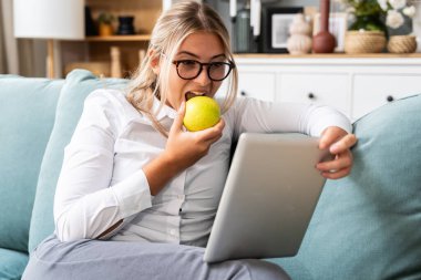 Evde dijital tablet üzerinde çalışan rahat bir iş kadını profesyonel meslekte serbest çalışan bir kadın, internette iş arama. Evden taşınmak, işten sonra uzak istihdam.