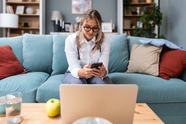Teletıp. Merkez büroda çalışan genç kadın doktor, özel pratisyen doktor, sağlık ve sağlık çalışanı kıdemli hastalarla iletişime geçmek için dizüstü bilgisayar kullanan.