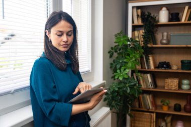 Ofisteki pencerenin yanında dijital tabletle duran mutlu genç kadın psikoterapist hastadan iyi haberlerle dolu bir e-posta aldıktan sonra heyecanlanıyor. Pozitif çevrimiçi psikoterapi sonuç kavramı