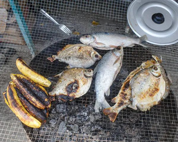 stock image Lima, Peru - Dec 3, 2023: Fresh fish and plantains cooking on a grill in the Amazonian Cantagallo district of Lima