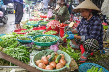 Hoi An, Vietnam - 5 Şubat 2024: Geleneksel Asya konik şapkaları giyen meyve ve sebze satıcıları, Hoi An pazarı, Vietnam