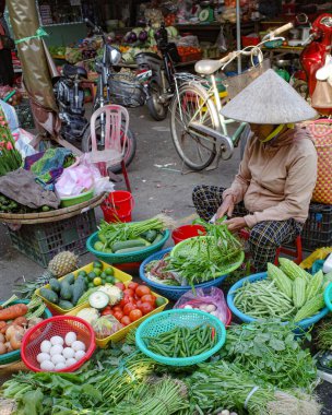 Hoi An, Vietnam - 5 Şubat 2024: Geleneksel Asya konik şapkaları giyen meyve ve sebze satıcıları, Hoi An pazarı, Vietnam